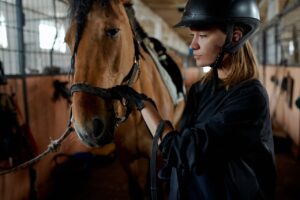 Pensive woman stroking horse in stable